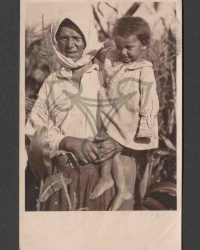 Bäuerin in Arbeitstracht mit Kleinkind auf dem Arm